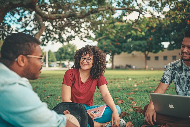 étudiante et étudiants assis dans l'herbe travaillant sur leur ordinateur portable